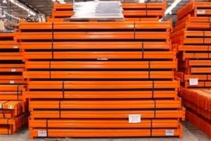 Orange coloured Used Pallet Racking Beams stacked in packs on top of one aother.